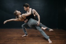 A couple performing a contemporary dance dynamic lift in a dance studio.