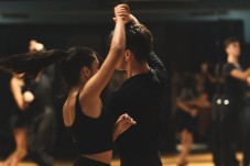 A couple practicing a salsa dance turn during a ballroom class.